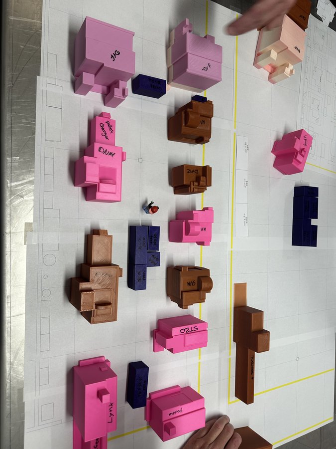 Scale 3D printed miniature CNC machines on blueprint grid with shop floor layout